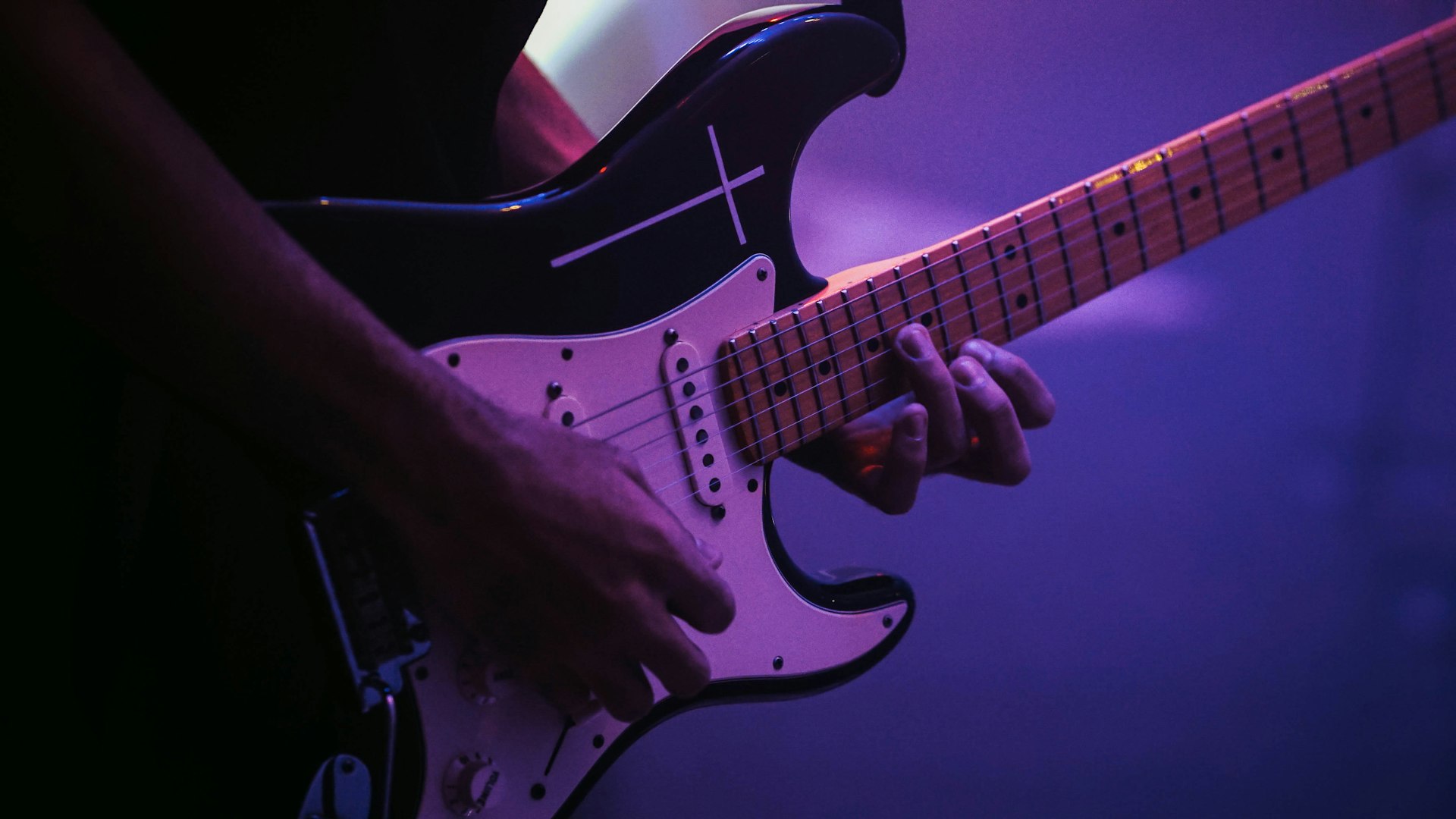 man playing black and white electric guitar